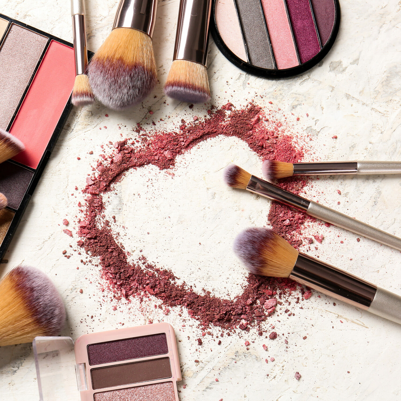 Set of makeup brushes and cosmetics on light background