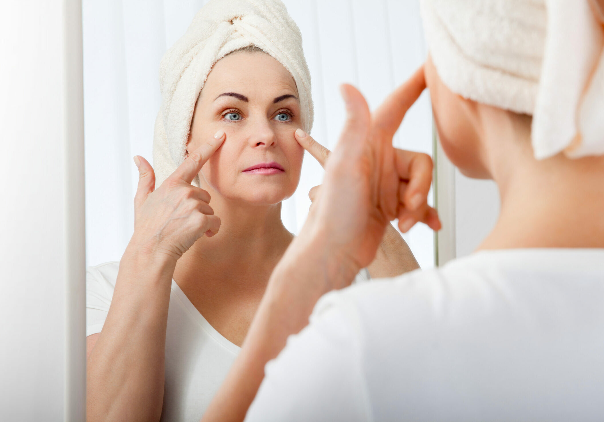 Middle aged woman looking at wrinkles in mirror. Plastic surgery and collagen injections. Makeup. Macro face. Selective focus on the face. Realistic images with their own imperfections.